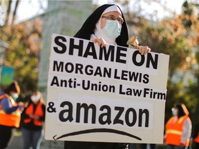 Jon Davidson dressed as a nun holds a banne ras people protest in support of the unionizing efforts of the Alabama Amazon workers, in Los Angeles, Calif., on March 22, 2021.