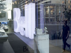 The reflection of a pedestrian is seen in a window of a Bell Canada store in Toronto.
