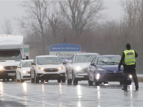 Quebec police stop motorists at a checkpoint near the Ontario border in Rivière Beaudette, west of Montreal, Sunday, March 29, 2020.