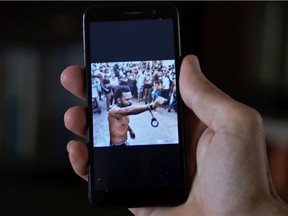 A man who did not want to be identified shows on his mobile phone an image displayed in social media of the rapper Maykel Osorbo with handcuffs clamped around one wrist, in Havana, Cuba, April 6, 2021.