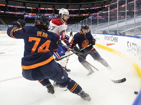 Edmonton Oilers' Ethan Bear and Gaetan Haas battle for the puck with Montreal Canadiens' Josh Anderson during first period in Edmonton on April 21, 2021.