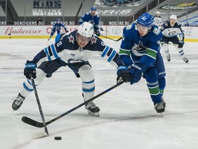 Canucks defenceman Quinn Hughes (43) plays for the puck against Winnipeg Jets forward Andrew Copp (9)at Rogers Arena in Vancouver on March 24, 2021.