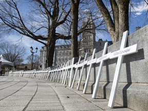 Crosses representing the 173 workers who died at work in 2021 are lined up during a tribute April 28, 2021, at the legislature in Quebec City.