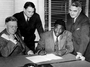 Jackie Robinson, first Black player in baseball's major leagues, signs with the Montreal Royals at the team's office at Delorimier Downs in Montreal on Oct. 23, 1945. From left are: Royals president Hector Racine; Branch Rickey Jr., head of the Brooklyn Dodgers' field staff; Robinson and Royals vice-president Roméo Gauvreau.