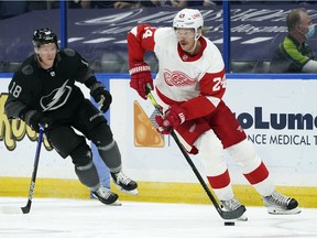 Detroit Red Wings defenceman Jon Merrill carries the puck around Lightning left wing Ondrej Palat during the second period on April 3, 2021, in Tampa.