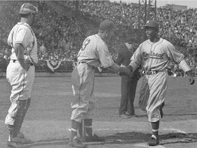 Montreal Royals second-baseman Jackie Robinson, right, crosses the plate at Roosevelt Stadium, in Jersey City, N.J., on April 18, 1946, after hitting a home run in the third inning against the Jersey City Giants. He's congratulated by Montreal outfielder George Shuba. The umpire is Art Gore.