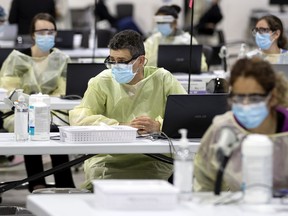 Health-care workers wait to administer the COVID-19 vaccine to the next batch of clients at the Bill Durnan Arena in Montreal on March 10, 2021.