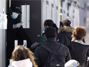 A security guard gives instructions to people waiting in a line for a COVID-19 test at the Montreal Jewish General Hospital on March 23, 2021.