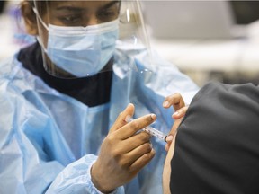 Navpreet Kaur injects a Montrealer with an AstraZeneca vaccine at the Bill Durnan arena on Thursday April 8, 2021 during the COVID-19 pandemic.