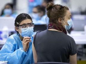 A health care worker checks on a woman as she administers the COVID-19 vaccination at the Bill-Durnan Arena in Montreal on April 21, 2021.