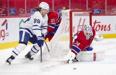 Goalie Jake Evans pokes the puck away from Toronto Maple Leafs' William Nylander during second-period action in Montreal on Monday May 3, 2021.