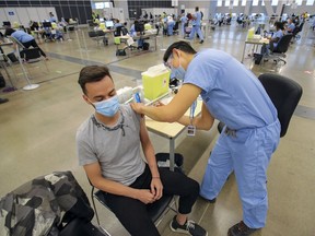 Keith Ferguson gets vaccinated against COVID-19 by Tian Lu at the Palais des congrès on Tuesday.