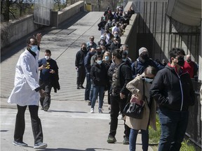 Yves Dorismond directs people outside the Olympic Stadium waiting to get their COVID-19 vaccination on Thursday.