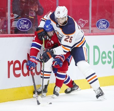 Edmonton Oilers' Darnell Nurse keeps Paul Byron in a head lock as they battle for the loose puck during first-period action in Montreal on Monday, May 10, 2021.