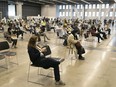 People sit and wait after receiving their Pfizer-BioNTech COVID-19 vaccine at the Palais des Congrès on Thursday May 13, 2021.