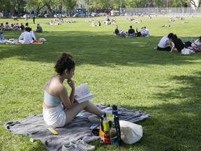 Lena Martinez reads her book at a crowded Jeanne-Mance park on Monday May 17, 2021 afternoon during the COVID-19 pandemic.