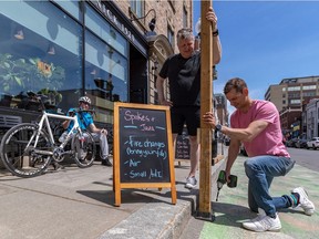 Chez Nick co-owner Nicos Kyriakopoulos, right, was quick to get to work erecting a terrasse outside his restaurant on Greene Ave. on Tuesday with the help of business partner Rob Callard. Cyclist Scott Macklin took a break and watched the men working.