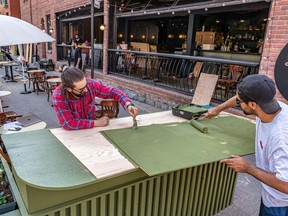 Restaurant La Prunelle workers Eric Berlin, left, and Anthony Gebrayel paint a part of the outdoor terrasse in Montreal on Wednesday May 19, 2021.