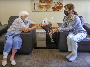 Lise Boissonneault, of Little Brothers West Island, brings flowers to Avril Withers (left) in the lobby of her apartment building in Dorval last week.