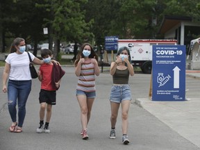 17 year old Sophie Fox (R) and her 15-year old sister Sarah (2nd R) give a thumbs up as they walk with brother Nicolas (12 years old) and mom Veronique Mauffette after all three siblings received their vaccine at Bill Durnan Arena on May 22, 2021.