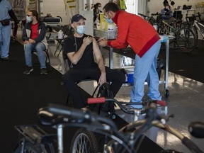 Yann Rabaud gets a COVID-19 vaccine from Mohamed Habbouche at a walk-in (or bicycle ride-in) vaccination centre at the Circuit Gilles Villeneuve on Saturday, May 29, 2021 in Montreal.