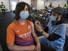 Raphaël Beaudoin gets a COVID-19 vaccine from Geoffrey Truchetti at a walk-in (or, rather, bike ride-in) vaccination centre at the Circuit Gilles-Villeneuve on Saturday, May 29, 2021.