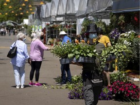 A flower vendor carries boxes of flowers to a client's car at the Atwater Market on May 20, 2021.
