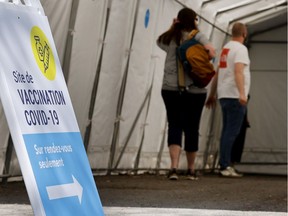 People line up to receive the COVID-19 vaccination at site setup in the Point St. Charles district of Montreal  on Tuesday, May 18, 2021.