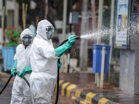 Members from the Telangana State wearing protective gear spray disinfectant on a street against the spread of the COVID-19 in Hyderabad, India, on April 19, 2021.