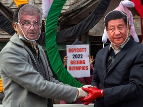Protesters wear masks of IOC President Thomas Bach, left, and Chinese President Xi Jinping during a demonstration against the 2022 Beijing Winter Olympics, in Dharmsala, India, in a file photo from Feb. 3, 2021.