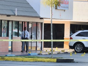 A Miami-Dade police officer investigates near shell case evidence markers on the ground where a mass shooting took place outside of a banquet hall on Sunday, May 30, 2021, in Hialeah, Fla.