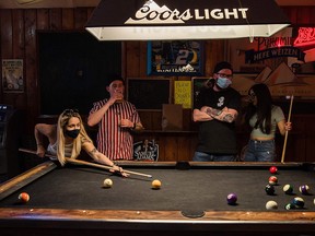 In this file photo taken on Feb. 13, 2021, people wearing masks play pool at Cheswick's West bar in Ocean Beach in San Diego.