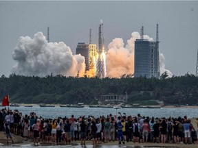 In this file photo taken on April 29, 2021, people watch a Long March 5B rocket, carrying China's Tianhe space station core module, as it lifts off from the Wenchang Space Launch Center in southern China's Hainan province. The Pentagon said Wednesday it is following the trajectory of a Chinese rocket expected to make an uncontrolled entry into the atmosphere this weekend, with the risk of crashing down in an inhabited area.
