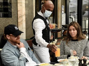 A waiter serves breakfast on the terrasse of Paris's landmark Café de Flore on May 19, 2021, as restaurant and bar terraces reopened at 50-per-cent capacity for groups of up to six. Mental health experts say people who feel anxious about gathering with people again should start slowly at their own rhythm.