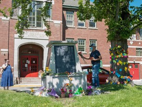 People lay flowers in front of the administration building at the former Kamloops Indian Residential School, after the remains of 215 children, some as young as three years old, were found at the site.