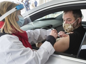 Alex Smirnov gets a COVID-19 vaccination from Annie Halinka Sanson at a demonstration of a drive-thru vaccination site on Tuesday, May 4, 2021  in Montreal.