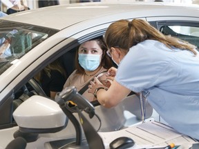 A motorist is vaccinated at a COVID-19 drive-thru clinic at the Circuit Gilles-Villeneuve in Montreal, on Wednesday, May 19, 2021. The clinic will officially open on Saturday, May 29.