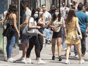 People enjoy the warm weather as they walk along Ste-Catherine St. Wednesday, May 19, 2021 in Montreal.