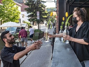 Restaurant La Prunelle owners Annie Tremblay passes flowers to her son, Felix Tremblay in Montreal on Wednesday May 19, 2021.