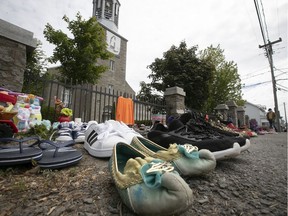 Children's shoes lie on the sidewalk leading to the St. Francis Xavier Mission Catholic Church in Kahnawake on Sunday, May 30, 2021. They where brought by residents to honour the 215 children whose bodies were buried on the grounds of a residential school in Kamloops, B.C.