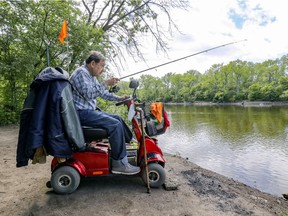 Robert fishes from his wheelchair on the shore of the the Riviere-des-Prairies at the l'Ïe-de-la-Visitation nature park in Montreal Monday May 31, 2021. (John Mahoney / MONTREAL GAZETTE) ORG XMIT: 66228 - 6707