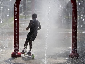 A young boy scooters through the splash pad installations during an early heat wave in Montreal, on Wednesday, May 27, 2020.