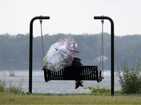 A steady rain does not keep a woman from enjoying the swings along the St. Lawrence River in the Verdun district of Montreal on Thursday, June 3, 2021.