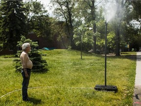 Raymond Plante, a Welcome Hall Mission resident, cools himself under a mist coming from a plastic pipe in a green space beside the mission in Montreal Sunday, June 6, 2021 on a hot afternoon. Montreal has issued a heat warning and is opening pools and splash pads to help people cool off during the heat wave from Sunday to Tuesday.