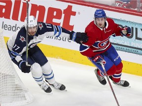 Canadiens' Alexander Romanov and Jets' Adam Lowry skate behind the Montreal net during Game 4 Monday night at the Bell Centre.