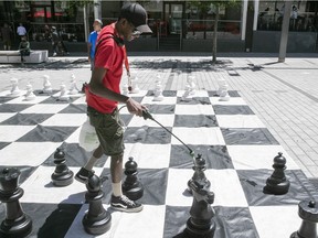 MONTREAL, QUE.: JUNE 10, 2021 --  Ghanais Muniandy sprays chess game at the Place des Festivals after another friendly game comes to a close on Thursday June 10, 2021 during the COVID-19 pandemic. (Pierre Obendrauf / MONTREAL GAZETTE) ORG XMIT: 66277 - 4646