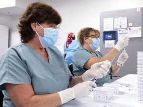 Nurses Ann Stirling, left, and Donna-Sue Kernohan work behind the scenes preparing vaccines at Décarie Square. Quebec has administered vaccine doses to 695,893 people in the past seven days.