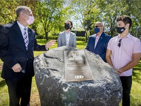 Mayor Alex Bottausci, left, speaks with the late Teresa Dellar's husband Gavin Fernandez and sons Jonathan and Nick, right, by the monument with a plaque of Dellar, a pioneer in palliative care and co-founder of the West Island Palliative Care Centre, following a ceremony renaming a park in her hnour in Dollard-des-Ormeaux.