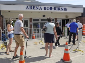 People line up to get into the COVID-19 vaccination clinic in the Bob-Birnie Arena in Pointe-Claire.