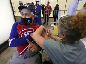 Habs fan Yann Etcheverry gets vaccinated by nurse Chantal Gosselin during walk-in vaccination clinic outside the Bell Centre prior to the Canadiens playoff game against the Vegas Golden Knights in Montreal Friday June 18, 2021.